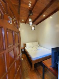 a small bedroom with a bed and a door at Glorias Panglao Inn 1 in Panglao Island