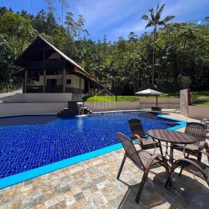 - une piscine avec des chaises et une table à côté d'une maison dans l'établissement Sítio Ribeirão Bonito, à Pinheiral