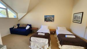 a attic room with two beds and a blue couch at Wintergreen 11 in Thredbo