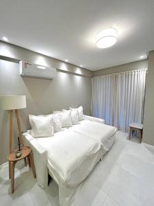 ein Schlafzimmer mit einem großen weißen Bett mit weißer Bettwäsche und Kissen in der Unterkunft Luxuoso Village em Guarajuba in Guarajuba