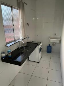 eine kleine weiße Küche mit einem Waschbecken und einem Waschbecken in der Unterkunft Apartamento mobiliado em Barreirinhas MA in Barreirinhas