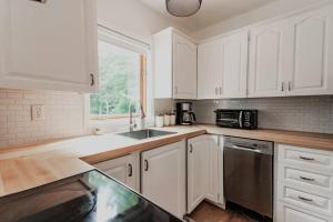 a kitchen with white cabinets and a sink and a microwave at Secret Hideaway 4BED Lakefront w/Hotub in Sheshegwaning