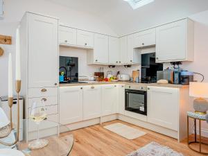 uma cozinha com armários brancos e piso em madeira em The Hideaway em Great Meols