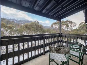 a balcony with two chairs and a view of the mountains at Tombarra 4B in Thredbo