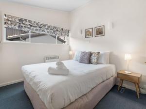 a bedroom with a white bed with a stuffed animal on it at Tombarra 4B in Thredbo