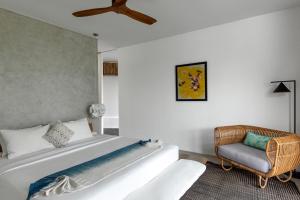 a bedroom with a large bed and a chair at Villa Nedine in Canggu