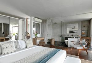 a bedroom with a large white bed and a bathroom at Villa Nedine in Canggu