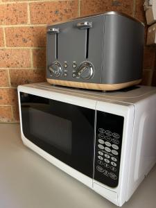 a toaster oven sitting on top of a microwave at Alexandra Motor Inn - Victoria Aus in Alexandra