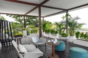 a patio with white chairs and tables and plants at Villa Nedine in Canggu