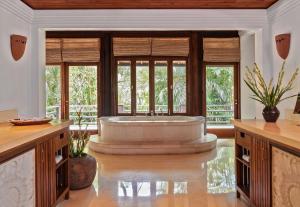 Habitación con ventanas y baño grande con bañera. en Villa Pangi Gita, en Canggu