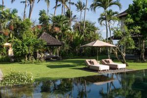 a resort with a pool with two lounge chairs and an umbrella at Villa Florimar - 50m to Seseh Beach in Canggu