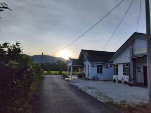a white house with the sun setting in the background at Mai Paddy Cottage, Balik Pulau in Balik Pulau