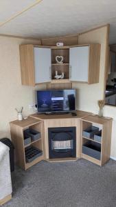 a room with a desk with a tv and a fireplace at 51 Oaklands caravan park dean thorness bay cowes in Porchfield