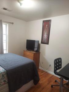um quarto com uma cama, uma televisão e uma secretária em Crystal Room 1 Guest House near 12mins to EWR airport / Prudential / NJIT / Penn station em Newark