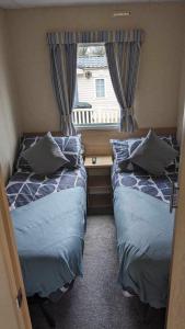 51 Oaklands caravan park dean thorness bay cowes في Porchfield: سريرين في غرفة صغيرة مع نافذة