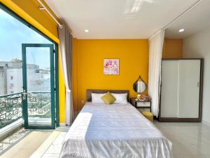 a bedroom with a bed and a yellow wall at Luxury Condotel Sai Gon 3 in Ho Chi Minh City