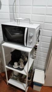 a microwave on a shelf with cups and mugs at fabio rooms 102 in Rome +12 photos