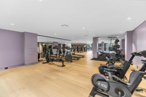 un gimnasio con cintas de correr y máquinas elípticas en 1Br Apt by Train&Shopping Pool&Gym with Water View en Sídney