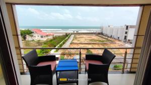 balcón con mesa, sillas y vistas al océano en Hotel Sagar Kanya INN, en Puri