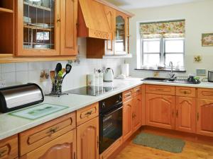 uma cozinha com armários de madeira e um forno com placa de fogão em Clover Cottage - Uk46269 em Tetney