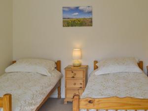 PortmahomackにあるSandy Bayのベッドルーム1室(ベッド2台、ランプ付きのナイトスタンド付)