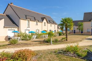 eine Reihe von Häusern mit Tischen und blauen Sonnenschirmen in der Unterkunft Lagrange Vacances Les Jardins Renaissance in Azay-le-Rideau