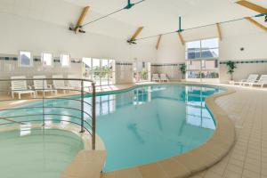 a large swimming pool with blue water in a building at Lagrange Vacances Les Jardins Renaissance in Azay-le-Rideau