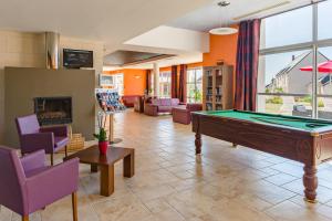 - un salon avec un billard et des chaises violettes dans l'établissement Lagrange Vacances Les Jardins Renaissance, à Azay-le-Rideau