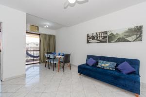 uma sala de estar com um sofá azul e uma mesa em Flat Posto 6 com Piscina - Copacabana no Rio de Janeiro