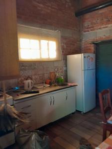La cuisine est équipée d'un réfrigérateur blanc et d'un évier. dans l'établissement El Serafín, à Cortaderas