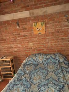 1 dormitorio con cama y pared de ladrillo en El Serafín en Cortaderas