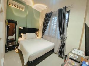 1 dormitorio con cama blanca y ventana en JIYO BOUTIQUE HOTEL by SAJIWA en Medan