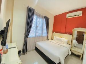 ein Schlafzimmer mit einem weißen Bett und einer roten Wand in der Unterkunft JIYO BOUTIQUE HOTEL by SAJIWA in Medan