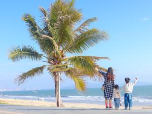 una familia de pie junto a una palmera en la playa en DoubleTree by Hilton Shanwei, en Shanwei