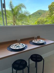 伊塔佩馬的住宿－Studio Flor do Mato，一个带两把椅子和两个盘子的柜台和一个窗口