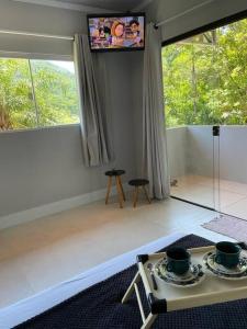 una sala de estar con 2 tazas sobre una mesa en Studio Flor do Mato, en Itapema