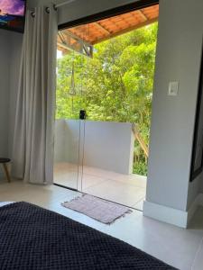 um quarto com uma porta de vidro para um quarto com árvores em Studio Flor do Mato em Itapema