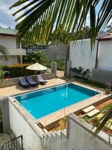 a swimming pool with two chairs and an umbrella at Erin Orr Villa in Wadduwa