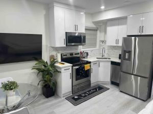 uma cozinha com armários brancos e electrodomésticos de aço inoxidável em Sun Light Kissed Cozy Suite - Modern Boho Paradise em Calgary