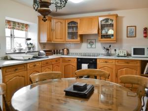 a kitchen with wooden cabinets and a table with chairs at Buttermilk Cottage - Uk46270 in Tetney