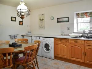 a kitchen with a table and a washing machine at Buttermilk Cottage - Uk46270 in Tetney