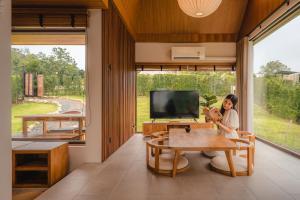 The CAMPIAN في شيانغ ماي: امرأة تجلس على طاولة في غرفة بها تلفزيون