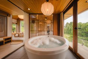Una bañera en una habitación con una ventana grande. en The CAMPIAN, en Chiang Mai 257 fotos más