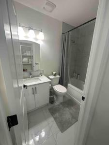 Sun Light Kissed Cozy Suite - Modern Boho Paradise في كالغاري: حمام ابيض مع مرحاض ومغسلة