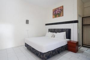 クタにあるシティ ガーデン バリ ドゥウィパ ホテルのベッドルーム1室(壁に絵が描かれた白いベッド1台付)
