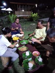 un grupo de personas sentadas alrededor de una mesa con comida en ROCA'S HOMESTAY Backpackers Chalet Bohol en Batuan
