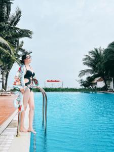 a woman sitting on a railing next to a swimming pool at Cam Bình Resort in Lagi