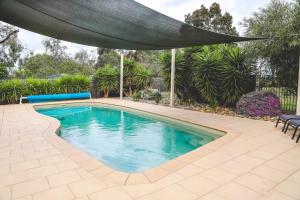 a swimming pool with an umbrella over it at Wharparilla House in Echuca
