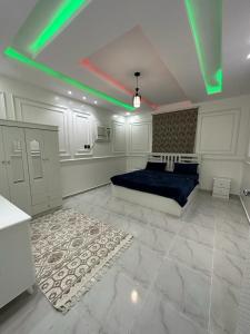 een slaapkamer met een bed met groene verlichting bij شاليه in Al Maʼish