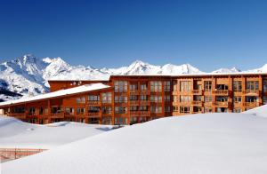a building in the snow with mountains in the background at Résidence Odalys Edenarc in Arc 1800